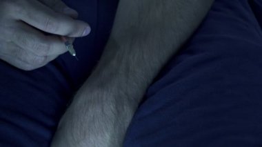 Uyuşturucu bağımlısı olduğunu, yerde oturur ve bir şırınga ile sonraki doz enjekte eden adam.