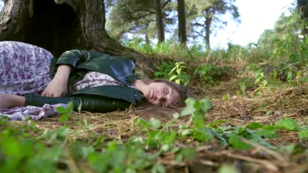 Une belle fille dort sous un grand arbre. Au premier plan il y a de l'herbe . — Video