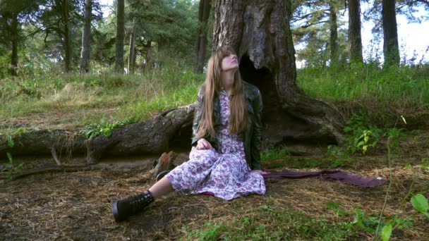 A beautiful girl sits under a large tree. The girl was lost. — Stock Video