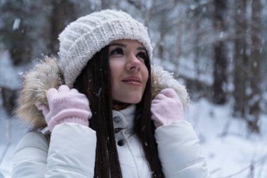 Bir kış ormanda kar yağışı sırasında yürüyüş beyaz ceket uzun siyah saçlı güzel kız