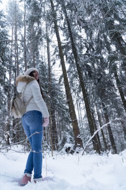 Bir kış ormanda kar yağışı sırasında yürüyüş beyaz ceket uzun siyah saçlı güzel kız
