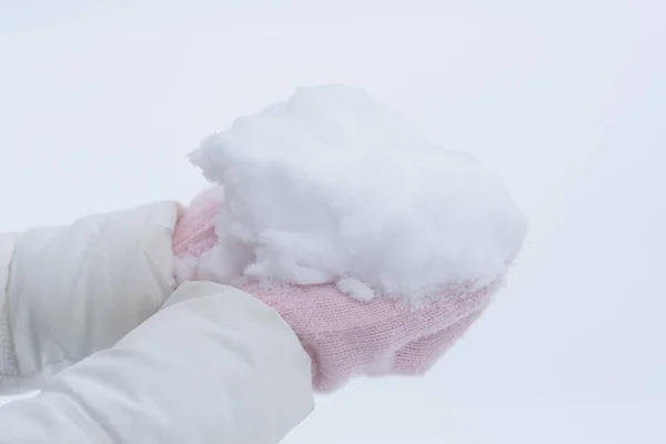 Handen in roze handschoenen houden sneeuw — Stockfoto