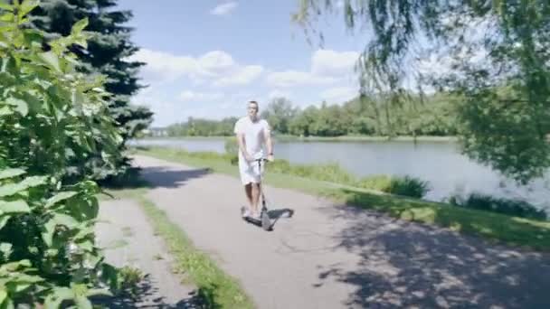 Багатоетнічний Чоловік Їде Електричним Скутером Вздовж Річки — стокове відео