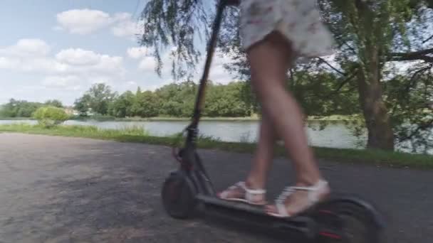 Багатоетнічна Дівчина Їде Електричним Скутером Вздовж Річки — стокове відео