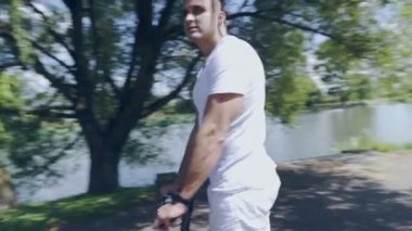 Çok ırklı bir adam nehir boyunca elektrikli scooter kullanıyor.