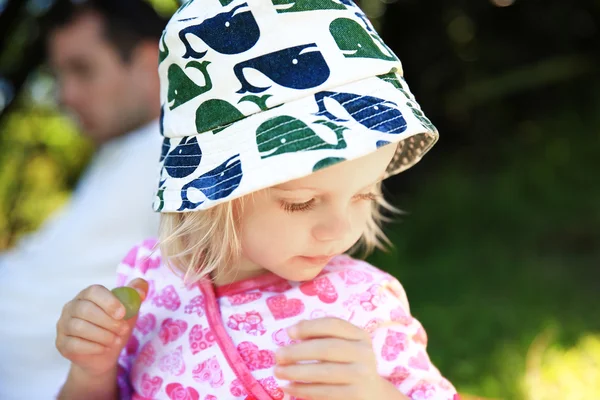 Entzückendes kleines Mädchen mit grünen Trauben in der Hand — Stockfoto