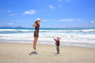 Sandy Beach üzerinde eğleniyor küçük kızı olan güzel kadın