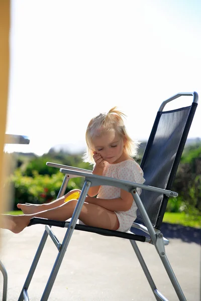 Outdoor-Foto von niedlichen kleinen Mädchen mit Sonnenbad am Stuhl — Stockfoto