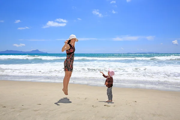 砂浜上で楽しんで小さな娘の若いきれいな女性 — ストック写真