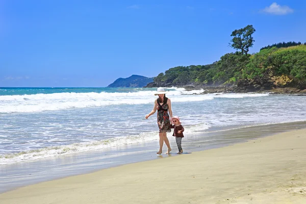 Молодий вродлива жінка з дочкою прогулянок уздовж піщаного пляжу — стокове фото