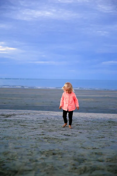 Hermosa chica de pelo rubio caminando en la playa de arena al amanecer — Foto de Stock