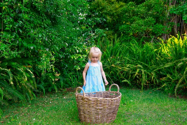 Little girl and big empty laundry basket outdoors — Stock Photo, Image