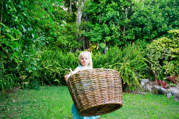 Little girl carrying big empty laundry basket — Stock Photo, Image