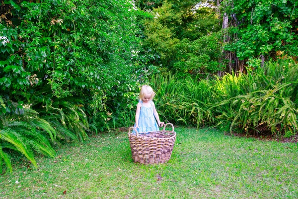 Klein meisje en grote lege wasmand buitenshuis — Stockfoto