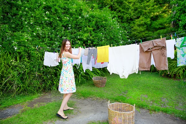 Lachende jonge vrouw opknoping Wasserij op waslijn in de achtertuin — Stockfoto