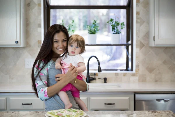 Portret van mooie brunette glimlachend met baby meisje in haar handen — Stockfoto