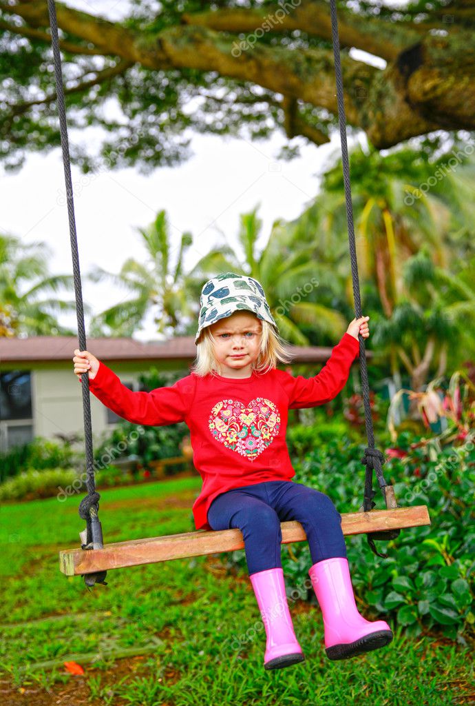 Cute Little Upset Girl Swinging On Wooden Swing Outdoors