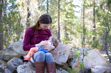 Young mother breastfeeding her baby outdoors clipart