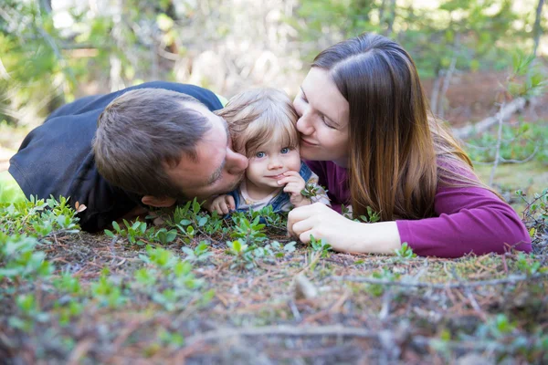 Šťastná rodina s batole dívka leží na zemi v lese — Stock fotografie