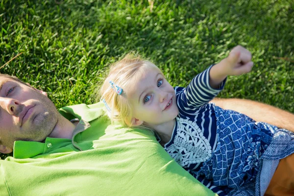 Молодой отец с дочкой лежит на траве в парке — стоковое фото