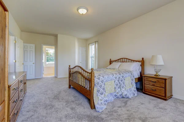 Spacious light tones bedroom with queen size wooden bed — Stock Photo, Image