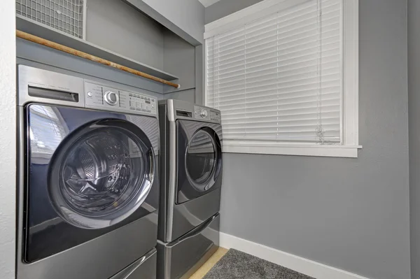 Interiér v prádelně s šedými stěnami, kobercem a moderními přístroji. — Stock fotografie