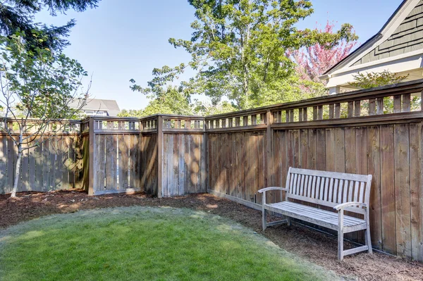 Maison cour arrière avec banc en bois debout près de la clôture — Photo