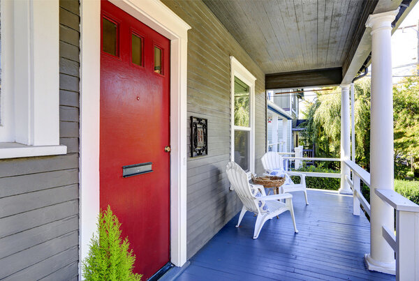 Entrance porch with white columns, blue wooden floor, red  door