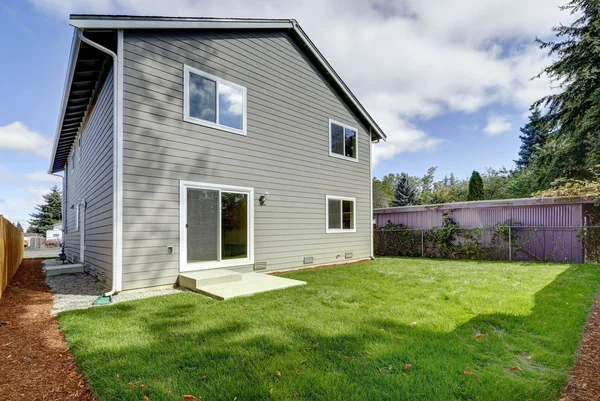 Backyard view of American two story house, gray exterior paint