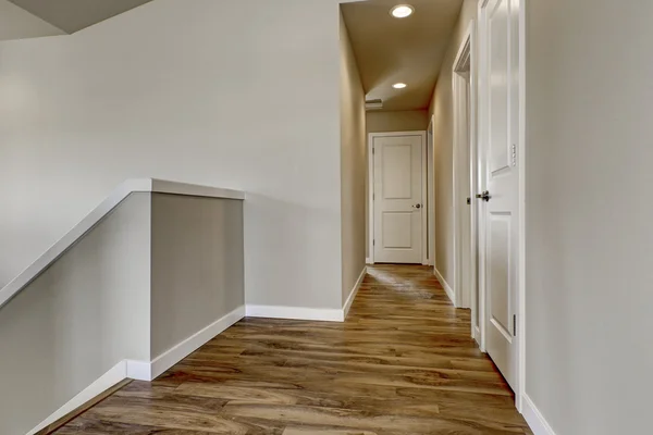 Empty hallway with hardwood floor, beige walls and staircase — ストック写真