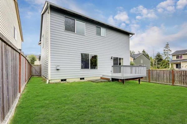 Small back yard with green grass and wooden fence — ストック写真