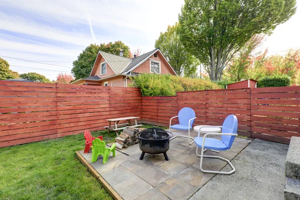 Fenced back yard with patio area and barbecue grill — ストック写真