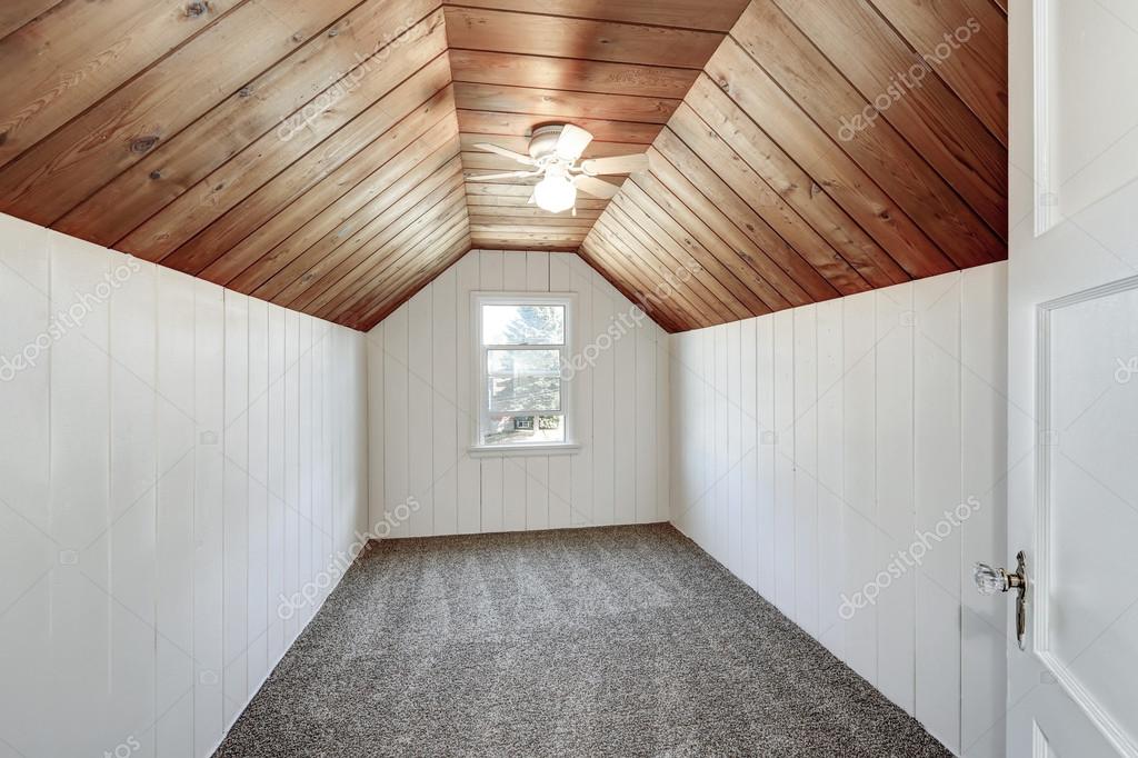 Small Empty Attic Room With Wood Paneling And Vaulted