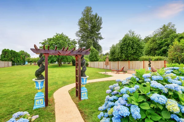 Красиво оформленные беседка и голубые цветы на заднем дворе — стоковое фото