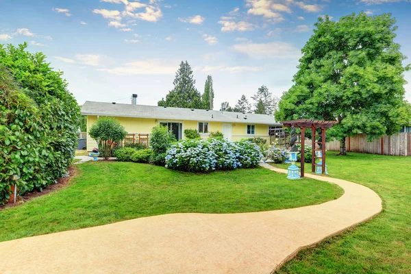 Trevligt inredda pergola och blå blommor i trädgården — Stockfoto