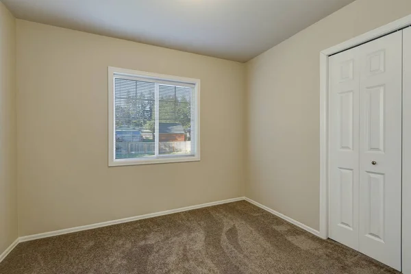 Vita dörrar garderob och ett fönster i tomt beige rum — Stockfoto