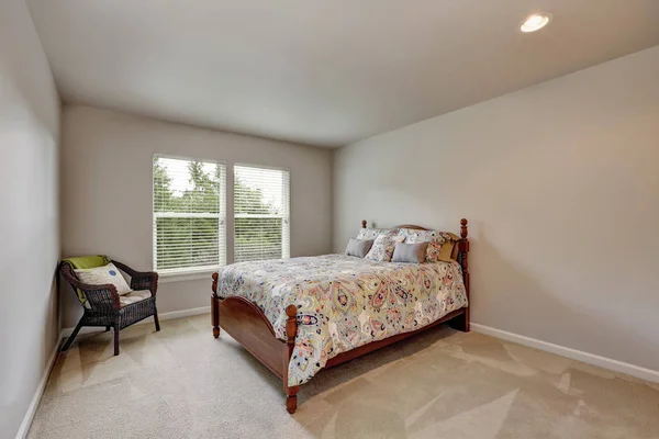 Enkla beige sovrum med färgglada säng och wicker stol. — Stockfoto