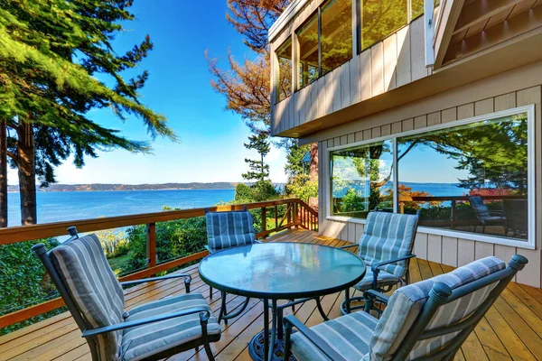 Glass top table with striped chairs on a wooden walkout deck. — Stock Photo, Image