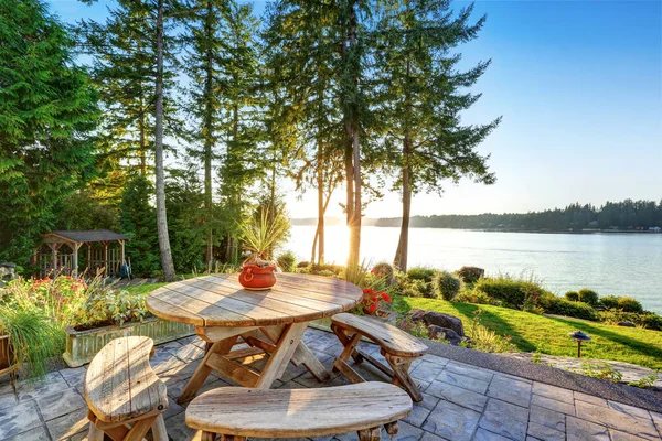 Back yard of waterfront house with rustic wooden table set — Stock Photo, Image