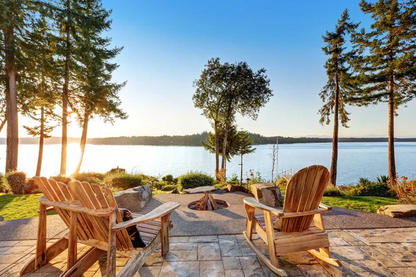 Cour arrière de maison au bord de l'eau avec chaises adirondack et foyer — Photo