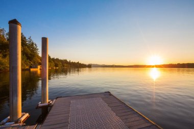 Göl günbatımı ve gökyüzü su yansıma üzerinde ahşap iskele.