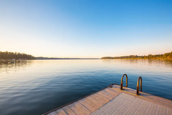 Fából készült móló a tó naplemente és az ég mérlegelés víz. — Stock Fotó