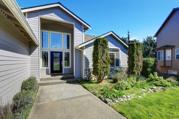 Blauwe gevelbekleding house met elegante voordeur en zijruiten — Stockfoto