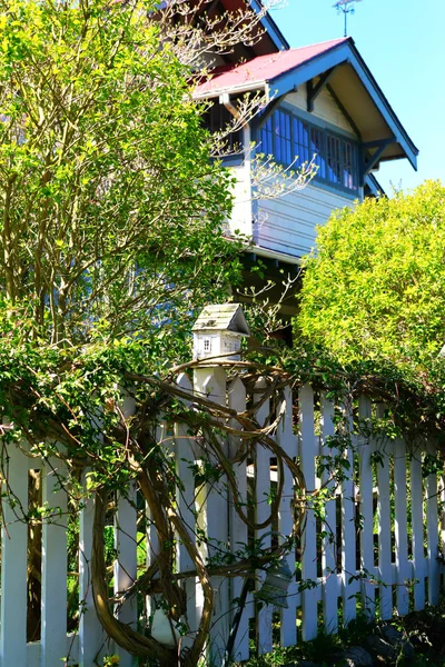 Maison d'oiseau en bois blanc sur un piquet de clôture — Photo