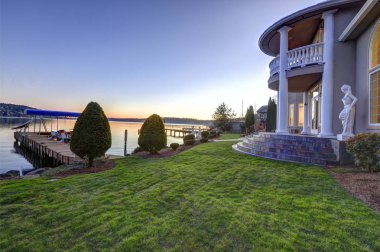 Luxurious waterfront home backyard view at sunset clipart