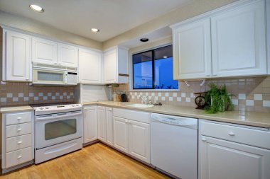 Beyaz mutfak tasarımı ile parke zemin ve beyaz aletleri