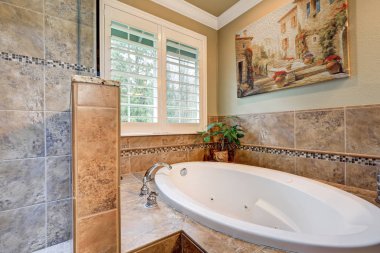 Lovely bathroom boasts jetted tub with a brown mosaic tile surround clipart