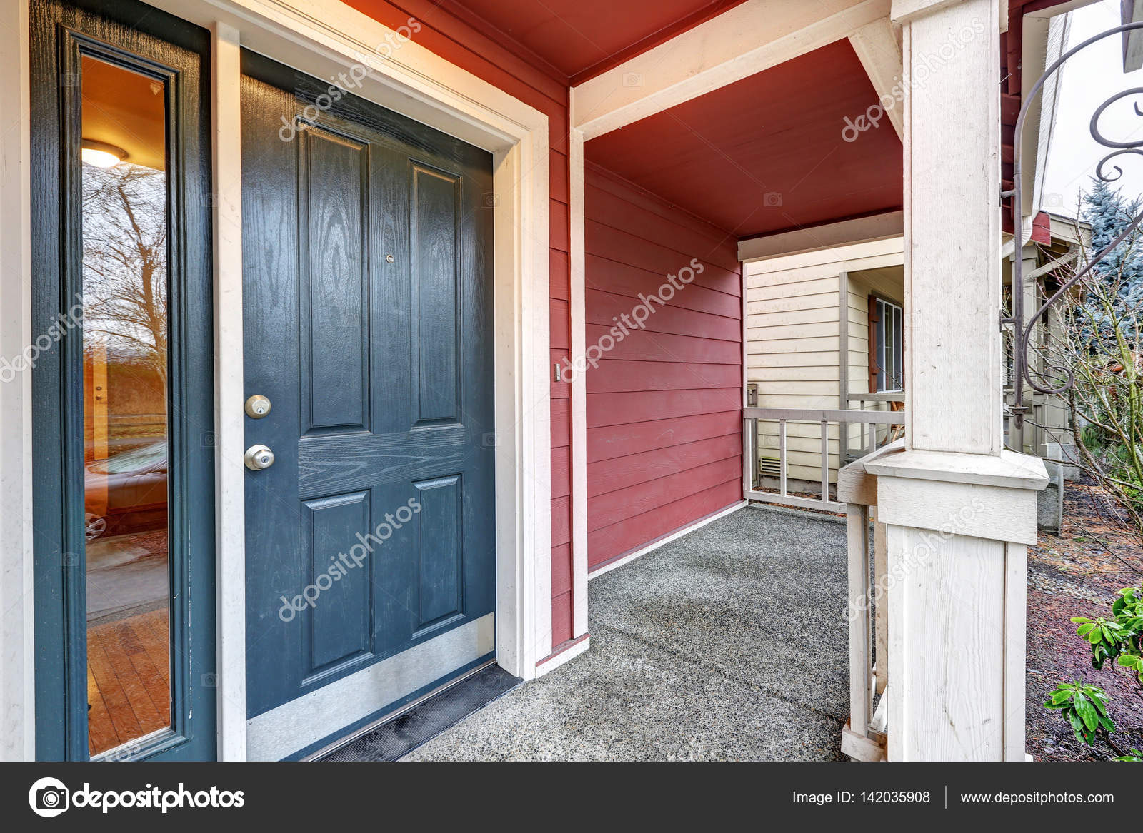 Covered Red Porch With Dark Blue Accent Front Door Stock Photo