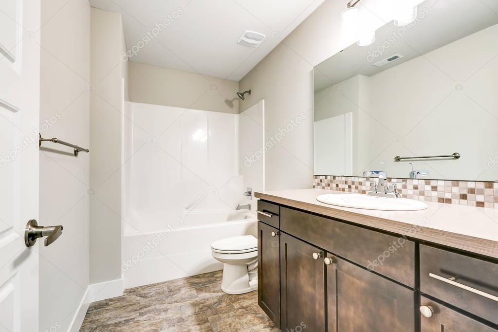 White bathroom interior with brown vanity cabinet