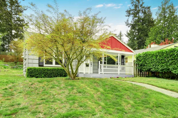 Encantador exterior de la casa con revestimiento verde y porche cubierto rojo . — Foto de Stock